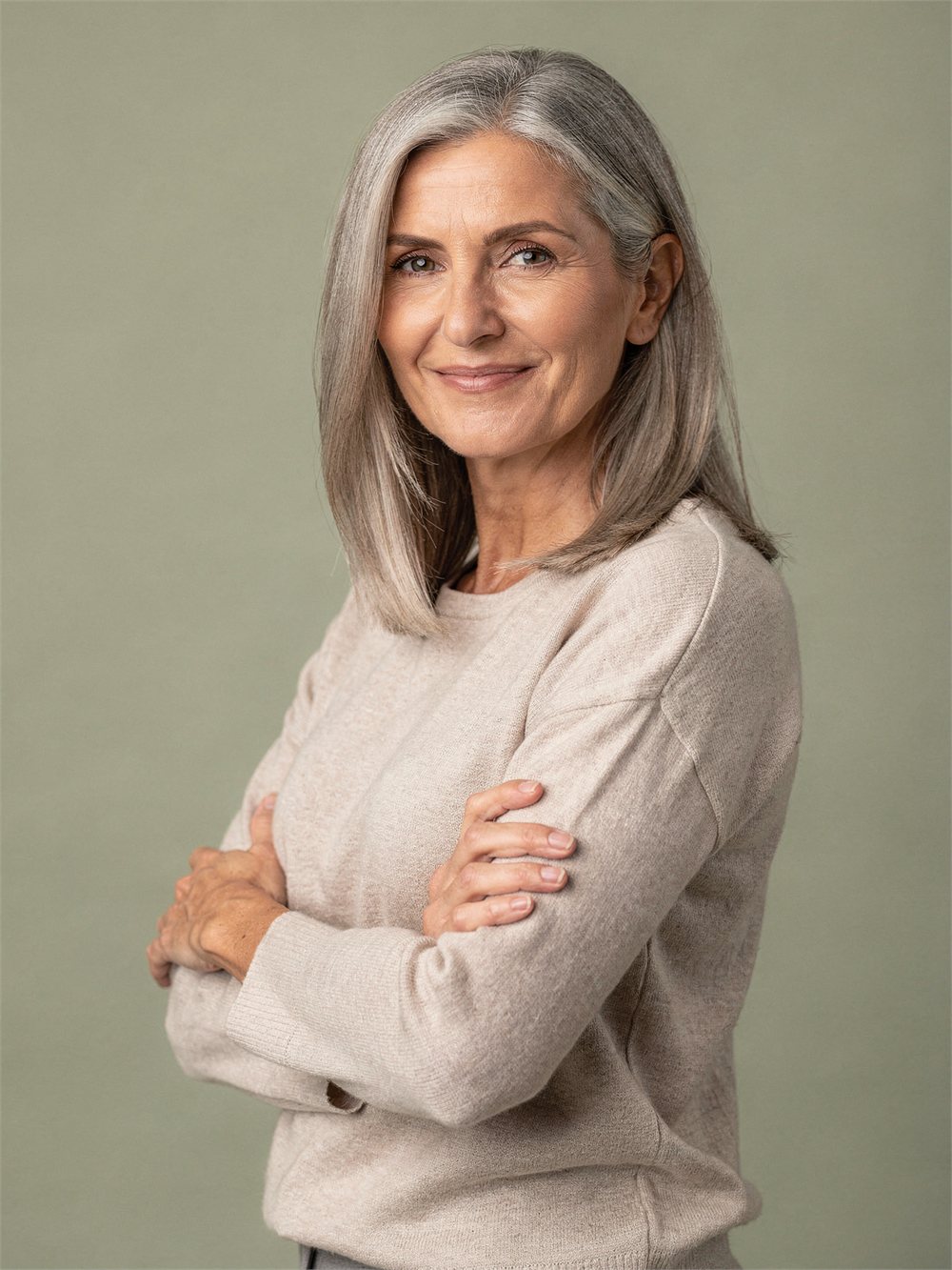 Woman with silver hair in an oat knit top against a soft sage background